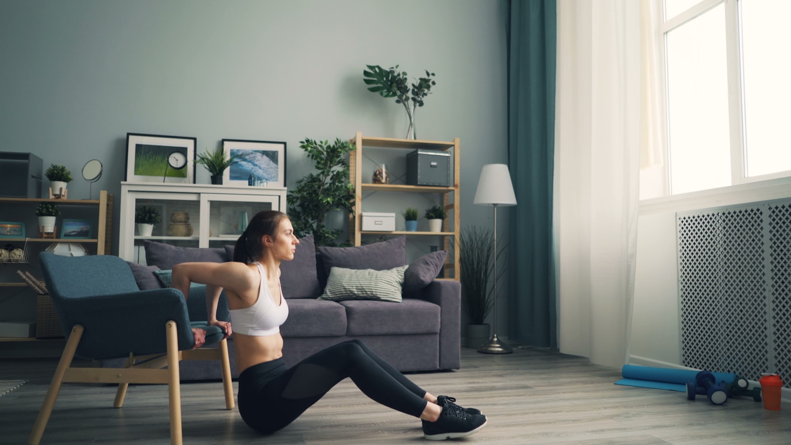 A woman training with dumbbells in her living room at home