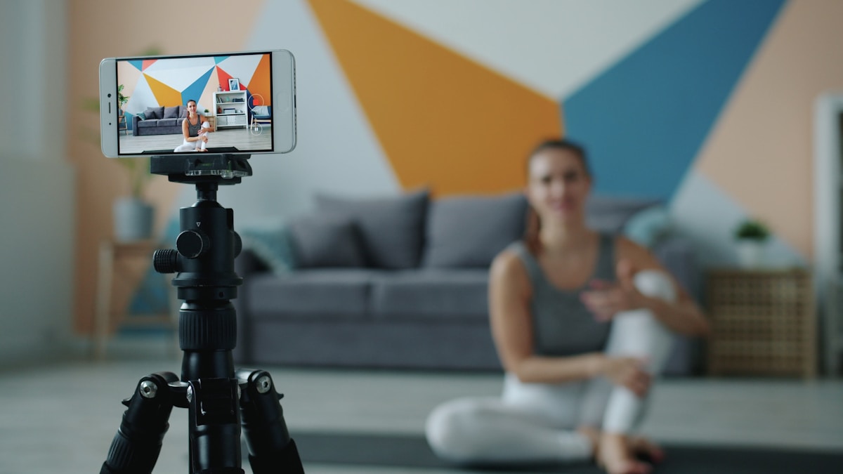 A woman filming her own personal training video on a phone mounted on a tripod